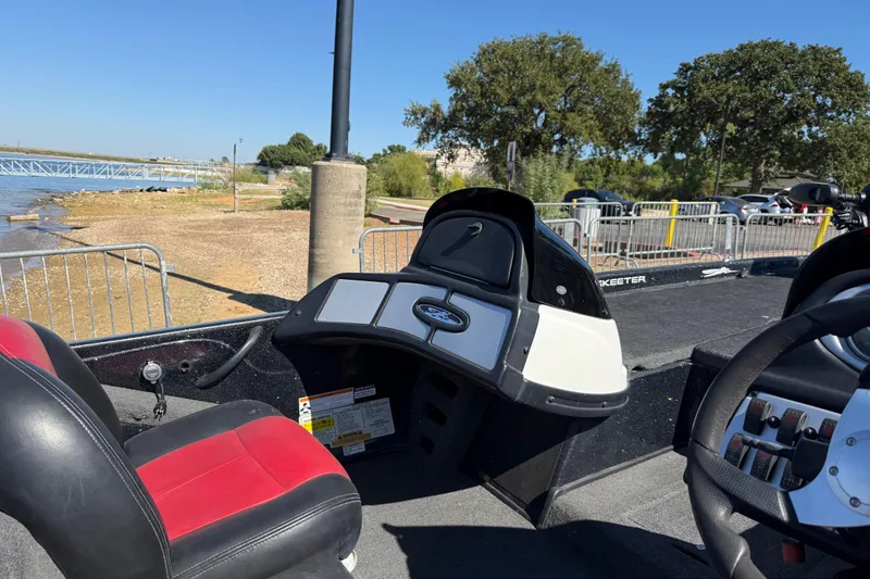 Slide: The Image of 2011 Skeeter ZX250 boat interior with red and black seats near a lakeside dock. - 81