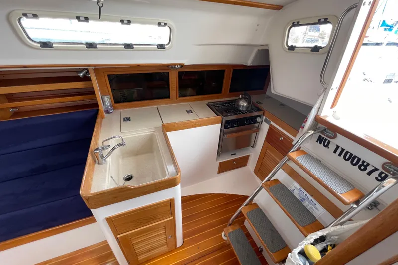 Slide: The Image of 2001 J Boats J/32 interior with compact kitchen, sink, stove, and wooden cabinetry. - 16