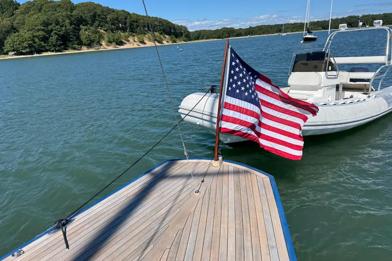 Slide: The Image of 2018 Leonardo Yachts Eagle 44 with American flag, docked near a motorboat on a sunny day. - 11