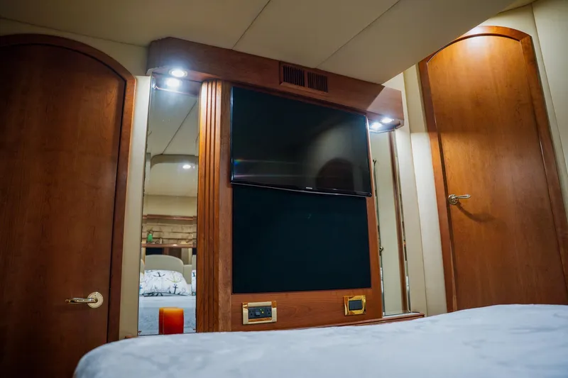 Slide: The Image of Luxurious 2002 Cruisers 5370 yacht interior with wood paneling and modern TV setup. - 34