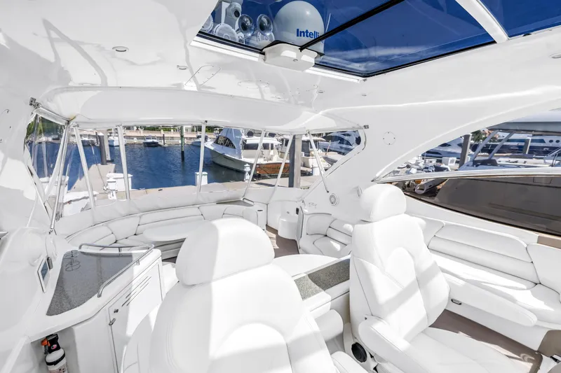 Slide: The Image of Luxurious 2002 Cruisers 5370 yacht interior with white seating and panoramic marina view. - 11