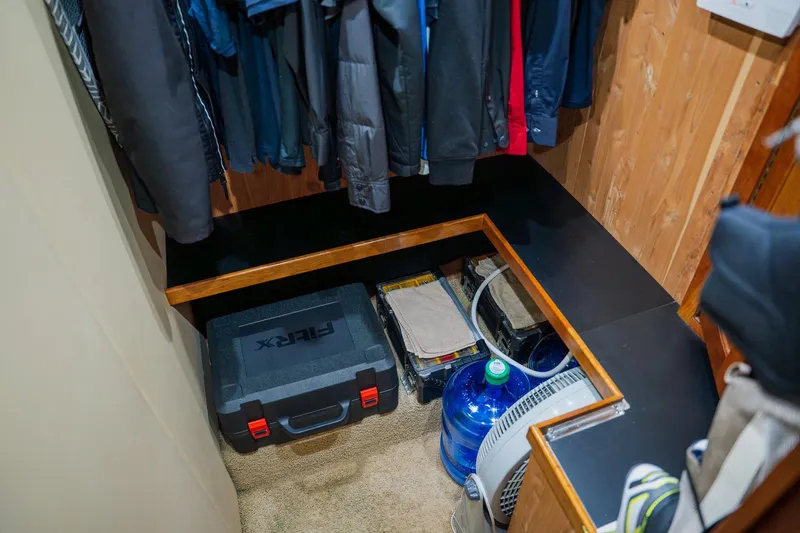 Slide: The Image of Storage area in a 2002 Cruisers 5370, featuring coats, tools, and water jug. - 37