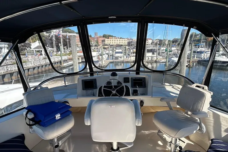 Slide: The Image of 2007 Mainship 34 Trawler helm with marina view, featuring comfortable seating and navigation controls. - 5