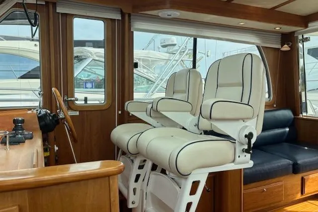 Slide: The Image of 2015 Sabre 42 Salon Express boat with striped seating and wooden table, docked by the water. - 1