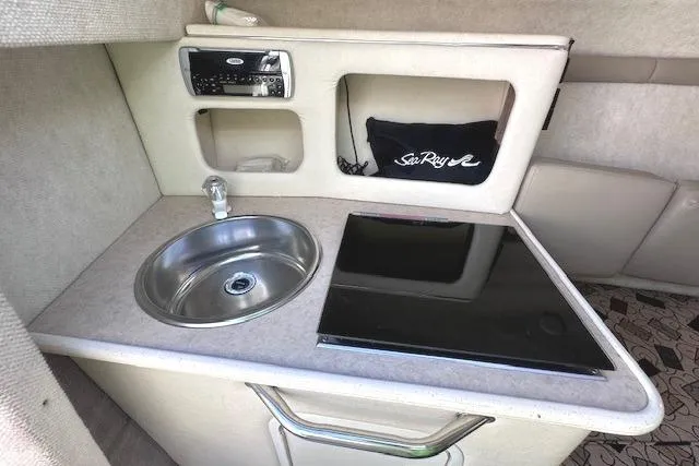Slide: The Image of 2001 Sea Ray 245 Weekender cabin kitchenette with sink, stove, and storage. - 26