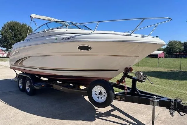 Slide: The Image of 2001 Sea Ray 245 Weekender boat on trailer, parked outdoors under clear blue sky. - 3