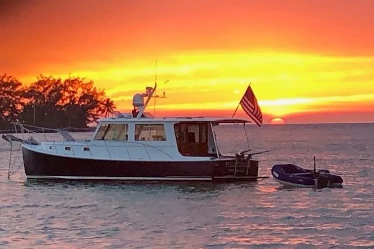 Slide: The Image of 2006 Duffy 37 Downeast boat at sunset with American flag on calm water. - 12