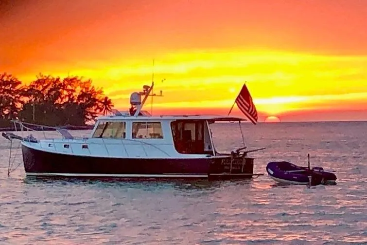 Slide: The Image of 2006 Duffy 37 Downeast boat at sunset with vibrant sky and American flag. - 71
