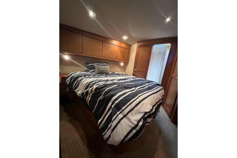 Slide: The Image of Luxurious bedroom in 2002 Ocean Yachts 56 Super Sport with striped bedding and wooden cabinets. - 23