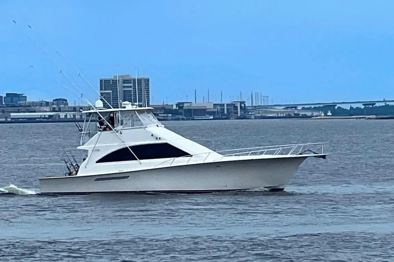 Slide: The Image of 2002 Ocean Yachts 56 Super Sport cruising on a calm waterway with cityscape background. - 59