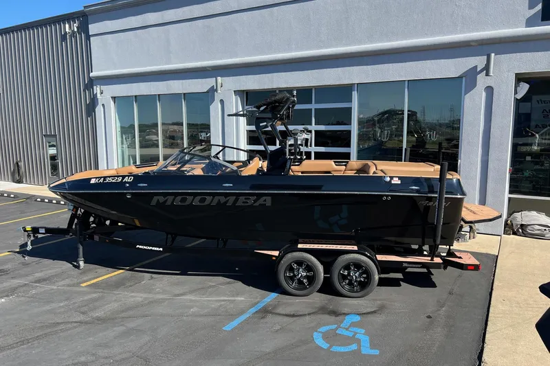 Slide: The Image of 2022 Moomba Makai boat on trailer outside dealership, black exterior, tan interior. - 2