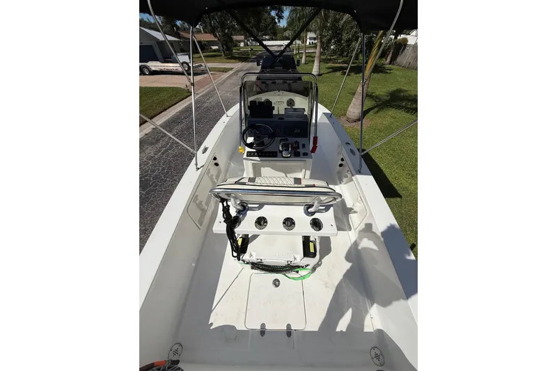Slide: The Image of 2002 Spectre 22CC boat interior with steering console and seating, parked on a residential street. - 11