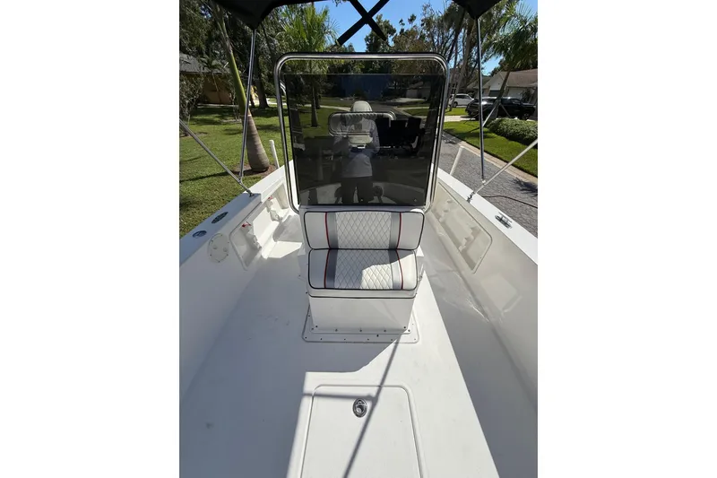 Slide: The Image of 2002 Spectre 22CC boat interior with cushioned seating and console, parked outdoors. - 8