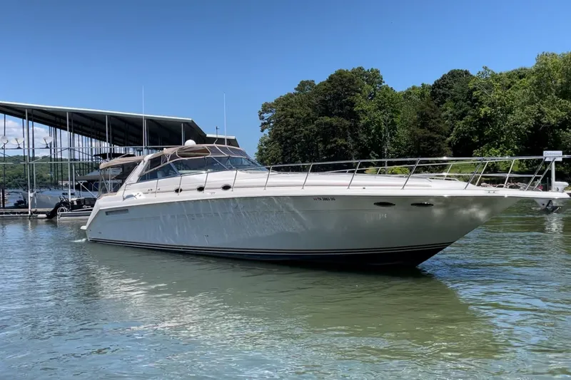 The Image of 1998 Sea Ray 500 Sundancer yacht docked on a sunny day, surrounded by trees. - 1