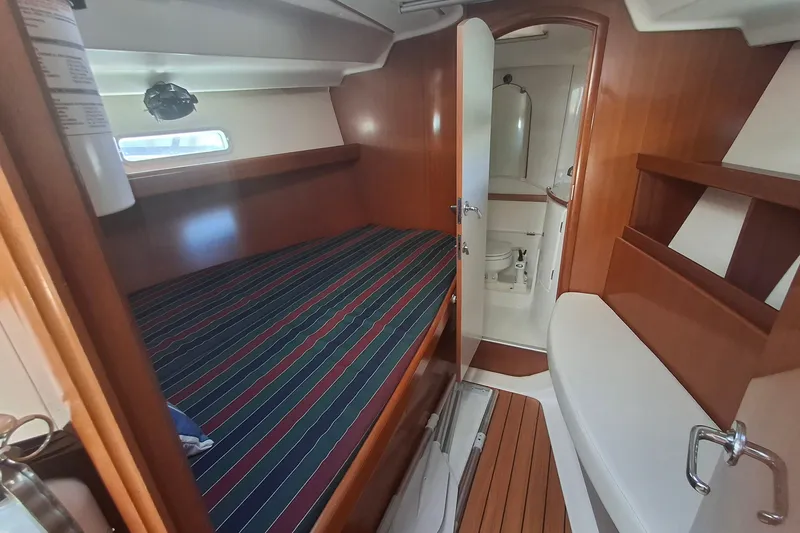 Slide: The Image of 2006 Beneteau Oceanis 393 cabin interior with striped bedding and ensuite bathroom. - 16