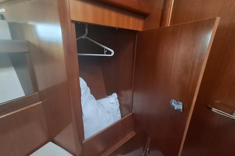 Slide: The Image of Wooden closet interior on 2006 Beneteau Oceanis 393 yacht, featuring hangers and bedding. - 19