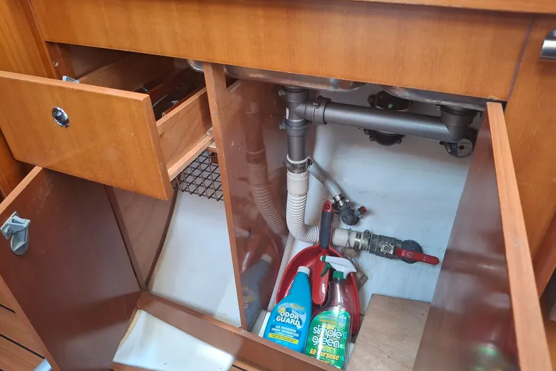 Slide: The Image of Open cabinet under sink in 2006 Beneteau Oceanis 393 yacht, showing plumbing and cleaning supplies. - 24