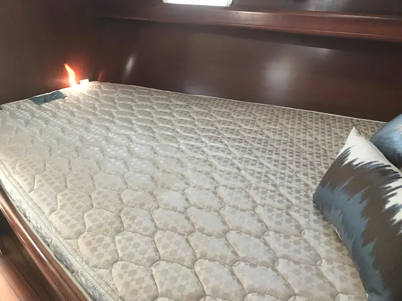 Slide: The Image of 2003 Beneteau 411 cabin with a comfortable mattress and decorative pillows. - 10