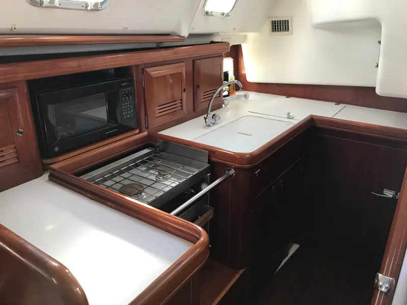 Slide: The Image of 2003 Beneteau 411 yacht kitchen with wood cabinetry, stove, microwave, and sink. - 4