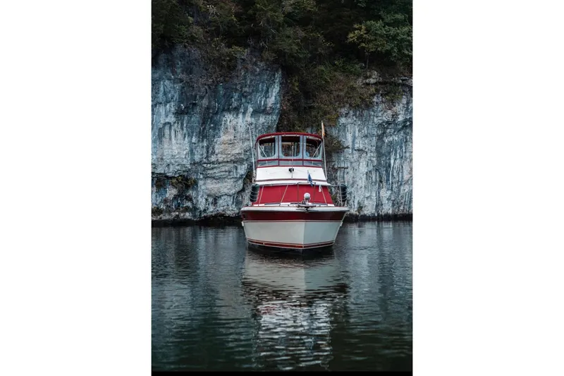 Slide: The Image of 1982 Trojan F-36 Convertible boat on calm water near rocky cliff. - 1