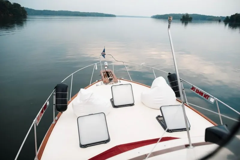 Slide: The Image of 1982 Trojan F-36 Convertible yacht cruising on a calm lake with scenic views. - 27