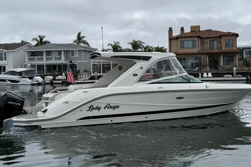 Slide: The Image of 2023 Sea Ray SLX 310 Outboard boat named "Lady Anya" docked near waterfront homes. - 0