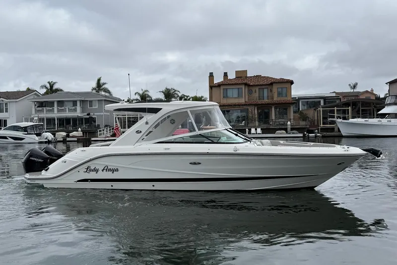 Slide: The Image of 2023 Sea Ray SLX 310 Outboard boat on calm water near waterfront homes. - 1
