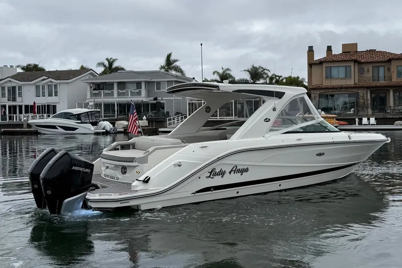 Slide: The Image of 2023 Sea Ray SLX 310 Outboard boat on calm water near waterfront homes. - 2