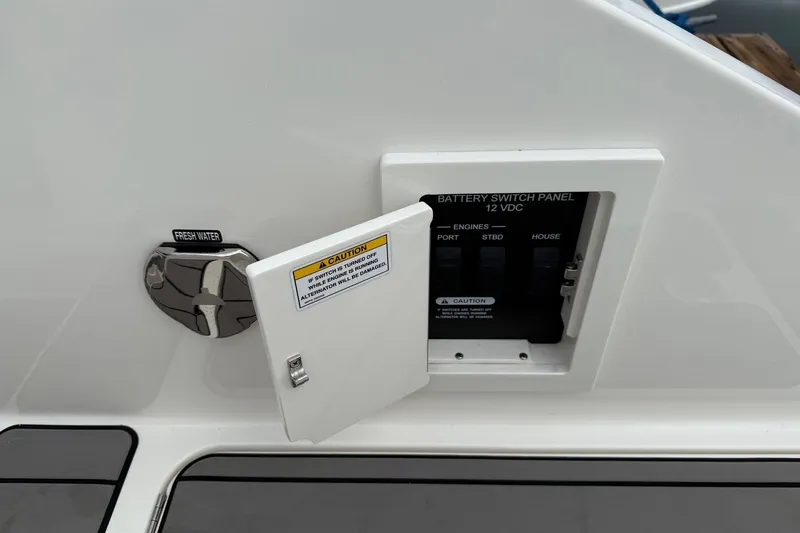 Slide: The Image of 2023 Sea Ray SLX 310 Outboard battery switch panel and fresh water access. - 22