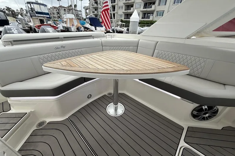 Slide: The Image of 2023 Sea Ray SLX 310 Outboard boat interior with elegant seating and wooden table. - 23