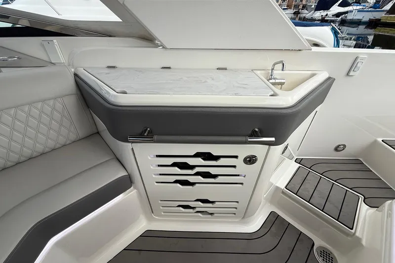Slide: The Image of 2023 Sea Ray SLX 310 Outboard interior with sink and seating area. - 29