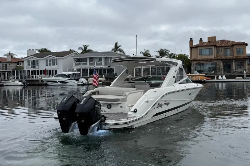 Slide: The Image of 2023 Sea Ray SLX 310 Outboard cruising in a residential waterfront area. - 3