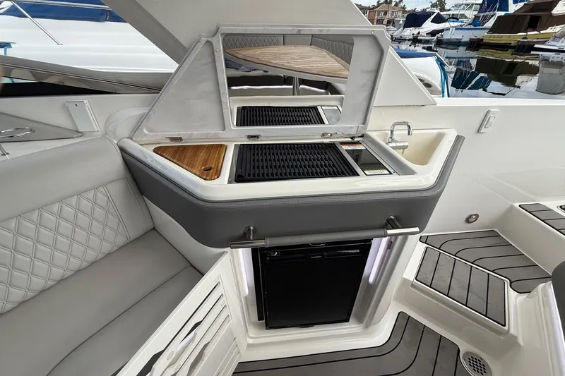 Slide: The Image of 2023 Sea Ray SLX 310 Outboard boat interior with kitchenette and seating area. - 30