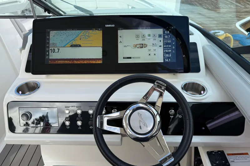 Slide: The Image of 2023 Sea Ray SLX 310 Outboard dashboard with navigation screens and steering wheel. - 36