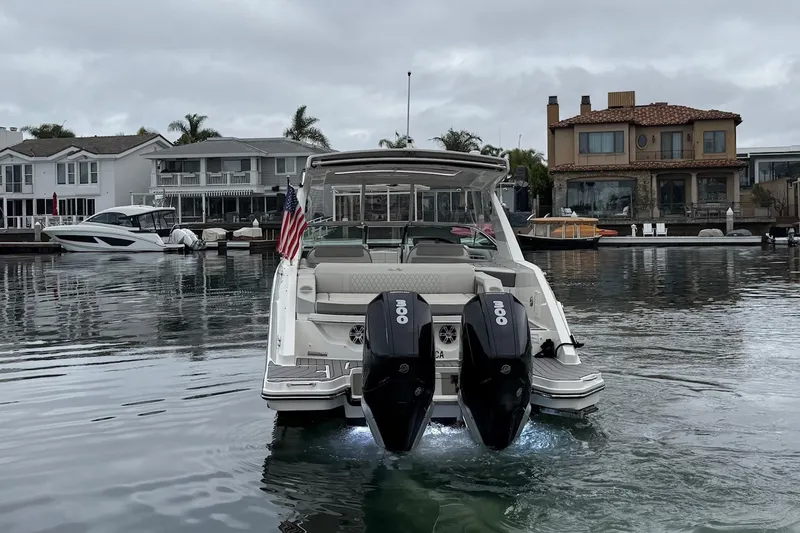Slide: The Image of 2023 Sea Ray SLX 310 Outboard boat docked in a scenic waterfront area. - 4