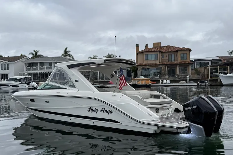 Slide: The Image of 2023 Sea Ray SLX 310 Outboard boat docked in a marina, featuring dual Mercury engines. - 6