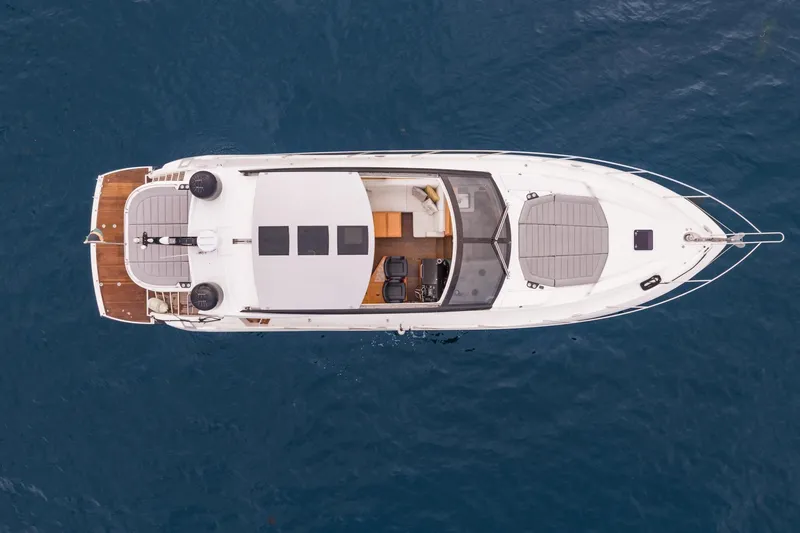 Slide: The Image of 2019 Sunseeker Predator 57 yacht cruising on calm waters near a scenic coastline. - 20
