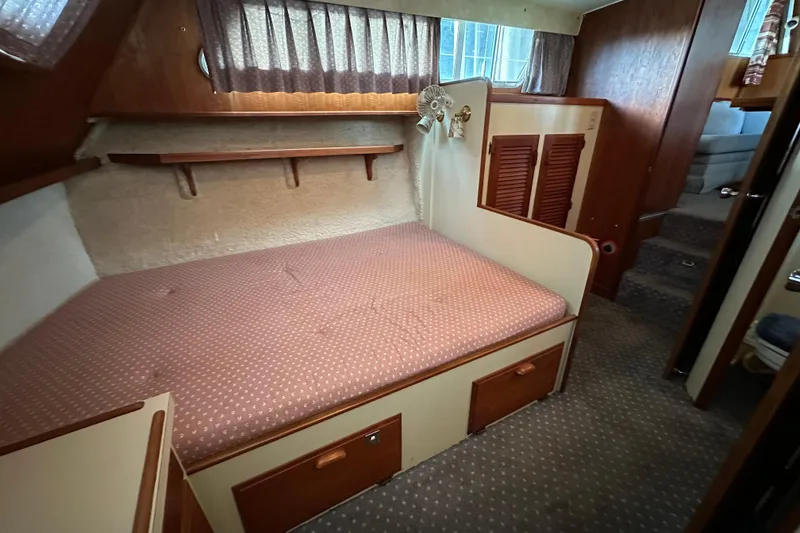Slide: The Image of 1984 Tollycraft 34 aft cabin interior with bed, wood paneling, and storage. - 14