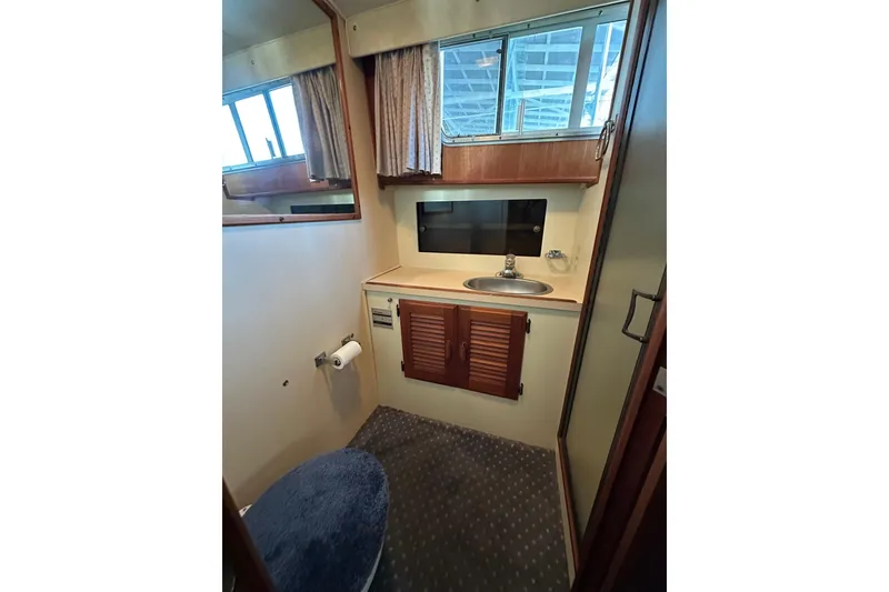 Slide: The Image of 1984 Tollycraft 34 aft cabin bathroom with sink, mirror, and storage cabinets. - 16