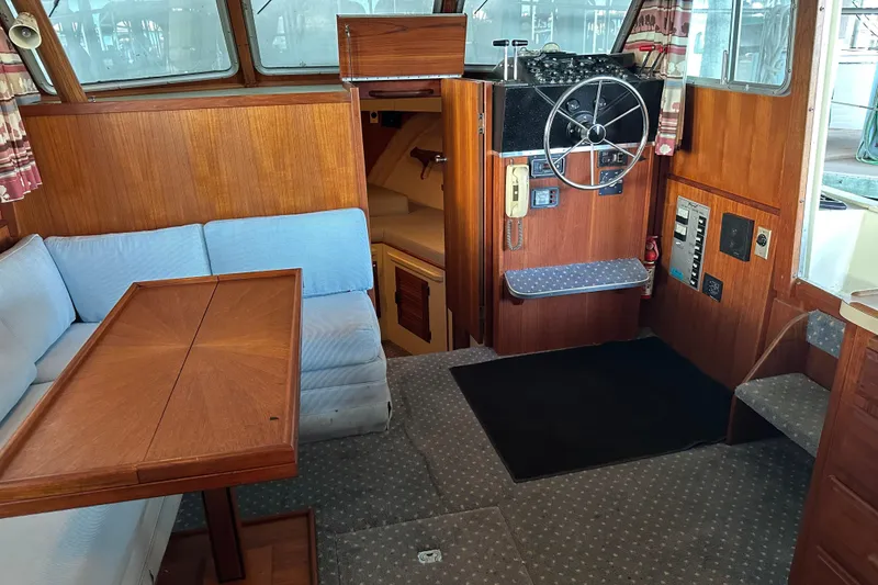 Slide: The Image of 1984 Tollycraft 34 aft cabin interior with wood paneling, steering wheel, and seating area. - 3