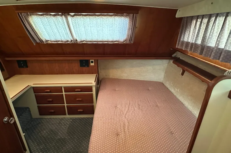 Slide: The Image of 1984 Tollycraft 34 aft cabin interior with bed, drawers, and curtains. - 4