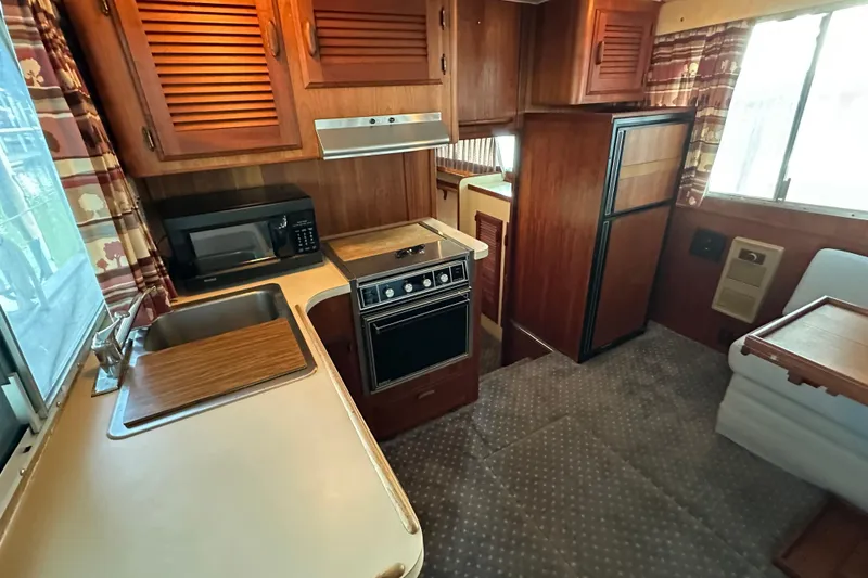 Slide: The Image of 1984 Tollycraft 34 aft cabin interior with kitchen, wood cabinetry, and appliances. - 8