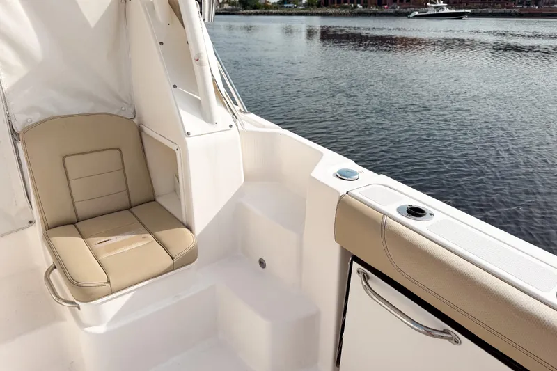 Slide: The Image of 2016 Pursuit OS 355 Offshore boat interior with beige seating by the water. - 15