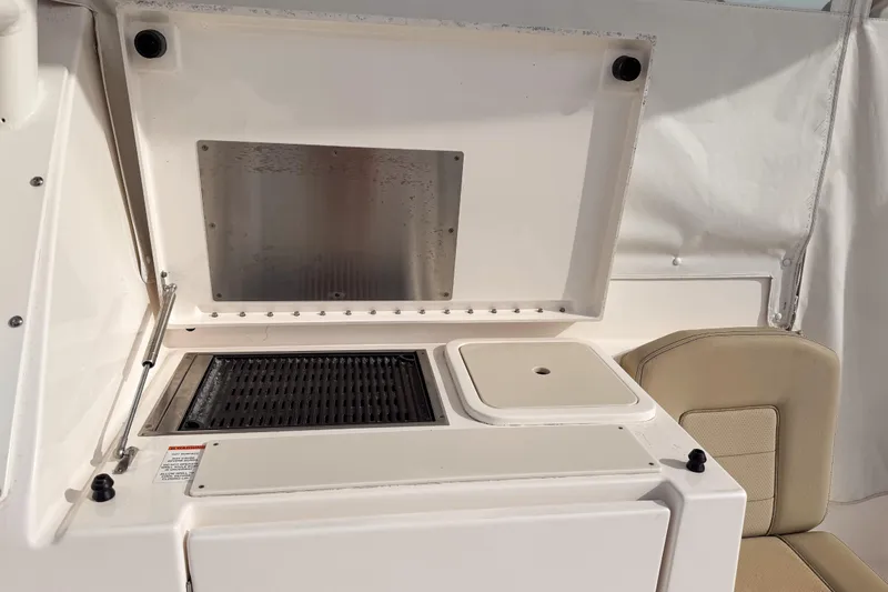 Slide: The Image of 2016 Pursuit OS 355 Offshore boat grill and sink area with beige seating. - 17