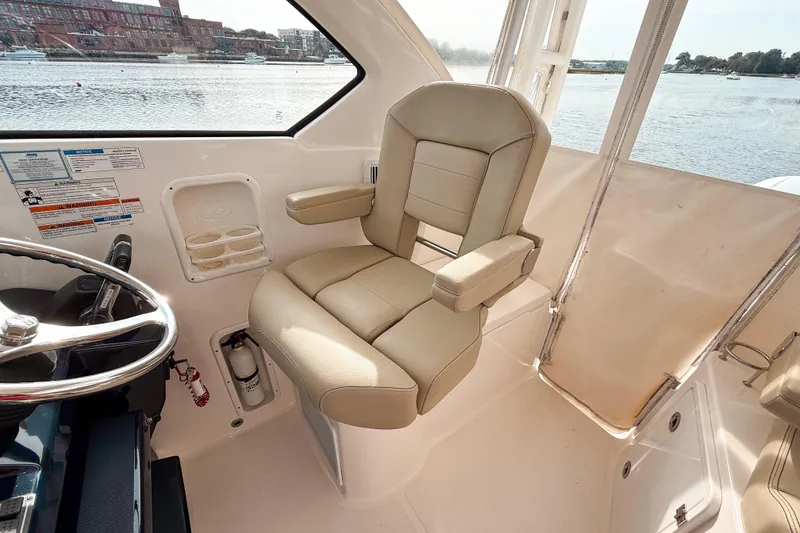 Slide: The Image of 2016 Pursuit OS 355 Offshore helm seat with steering wheel, overlooking waterfront. - 20