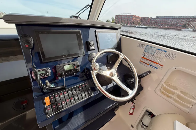 Slide: The Image of 2016 Pursuit OS 355 Offshore helm with steering wheel, navigation screens, and control panel. - 24