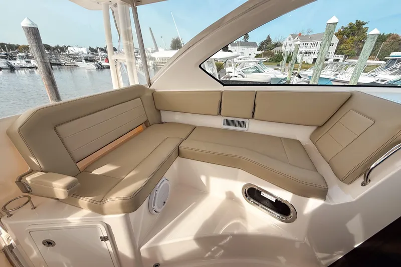 Slide: The Image of 2016 Pursuit OS 355 Offshore boat interior with beige seating, docked at marina. - 26