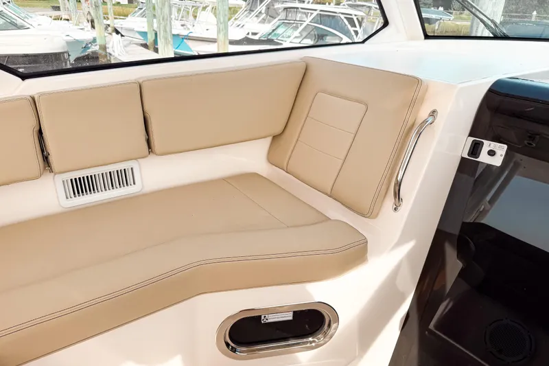 Slide: The Image of 2016 Pursuit OS 355 Offshore boat interior with beige seating and window view. - 27