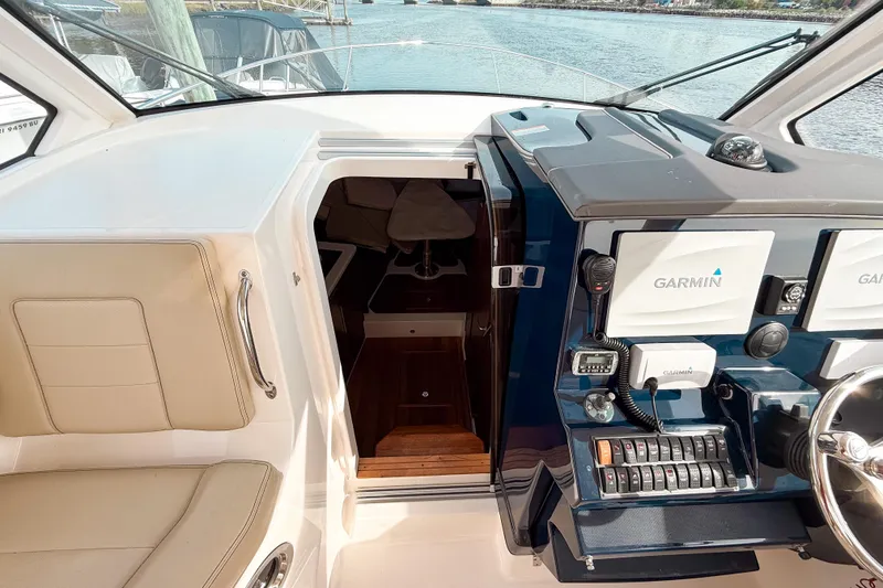 Slide: The Image of 2016 Pursuit OS 355 Offshore helm with Garmin navigation, beige seating, and cabin entrance. - 31