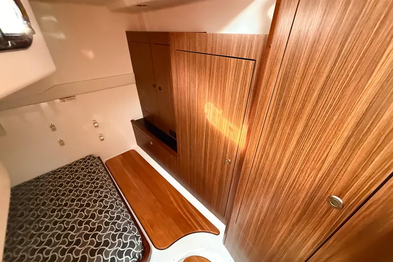 Slide: The Image of 2016 Pursuit OS 355 Offshore cabin interior with wood paneling and patterned bedding. - 38